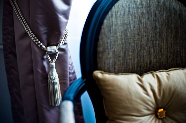 Curtain tassel tie-back and a gold cushion with an amber crystal on an upholstered chair