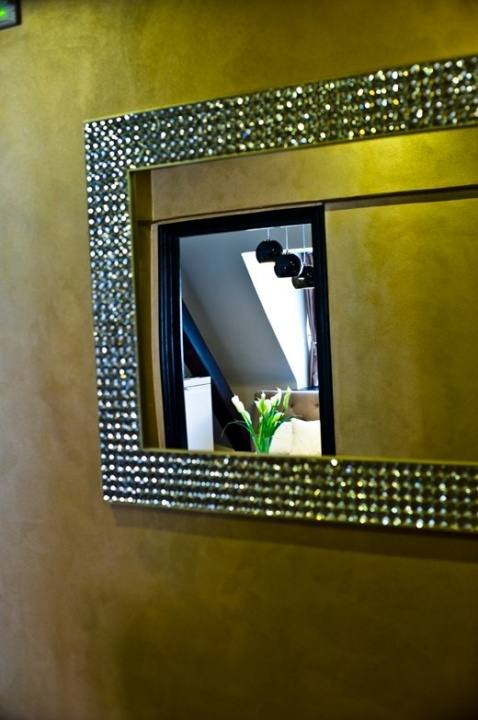Mirror framed in sparkling crystals on a gold Venetian-plaster wall