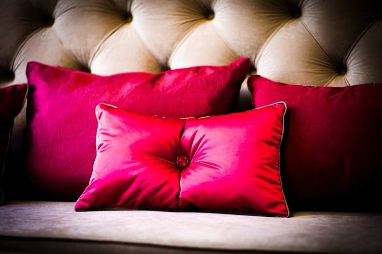 Crimson satin cushions on a beige button-tufted sofa