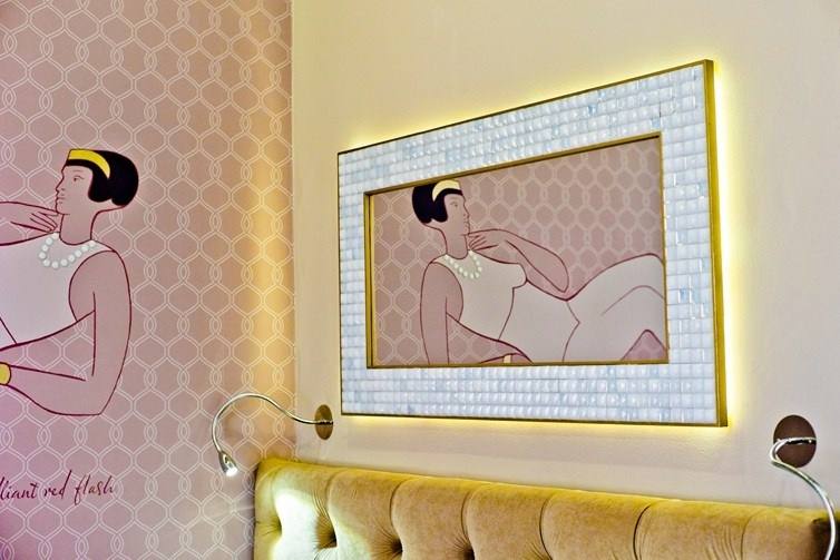 Art Deco drawing of a woman with pearls and a mother-of-pearl mosaic mirror above a tufted headboard