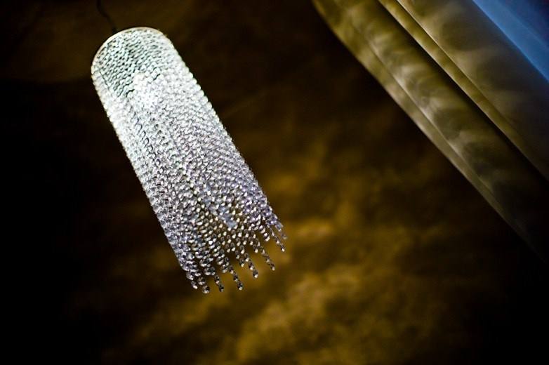 Crystal pendant light against a gold stucco wall