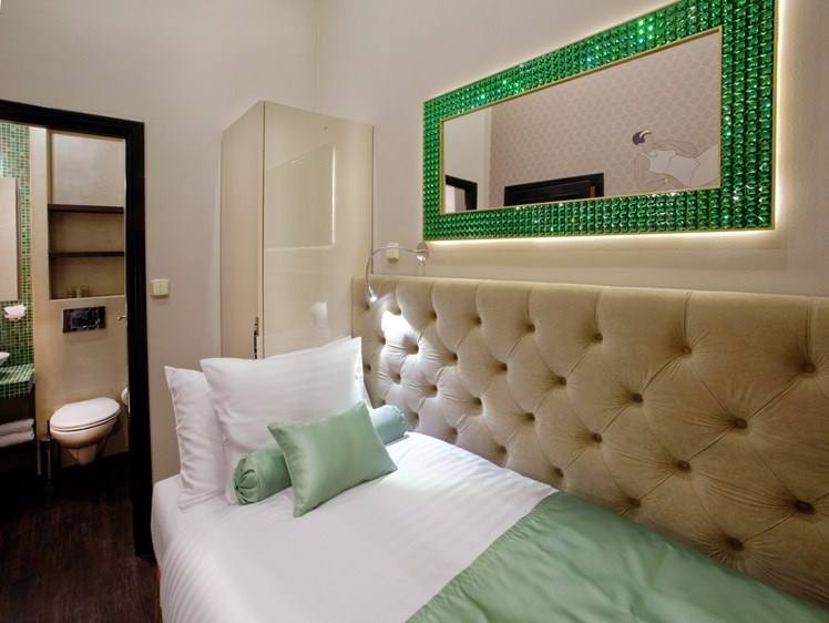 Emerald single room with a tufted headboard and an emerald-crystal framed mirror