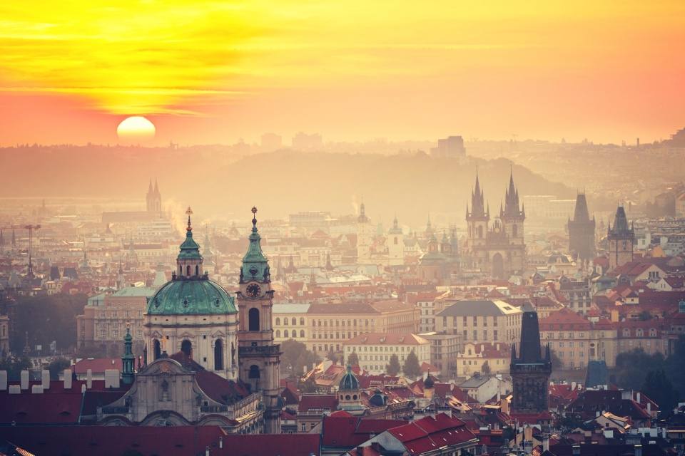 Sunrise over Prague rooftops with the dome of St Nicholas Church and the spires of Týn Church