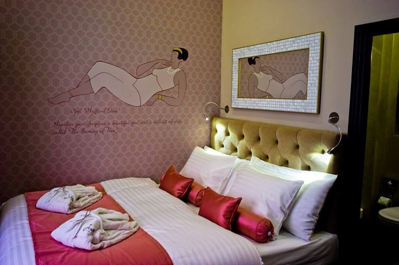 Bed in the Opal room with bathrobes, coral cushions and the painted opal legend on the wall