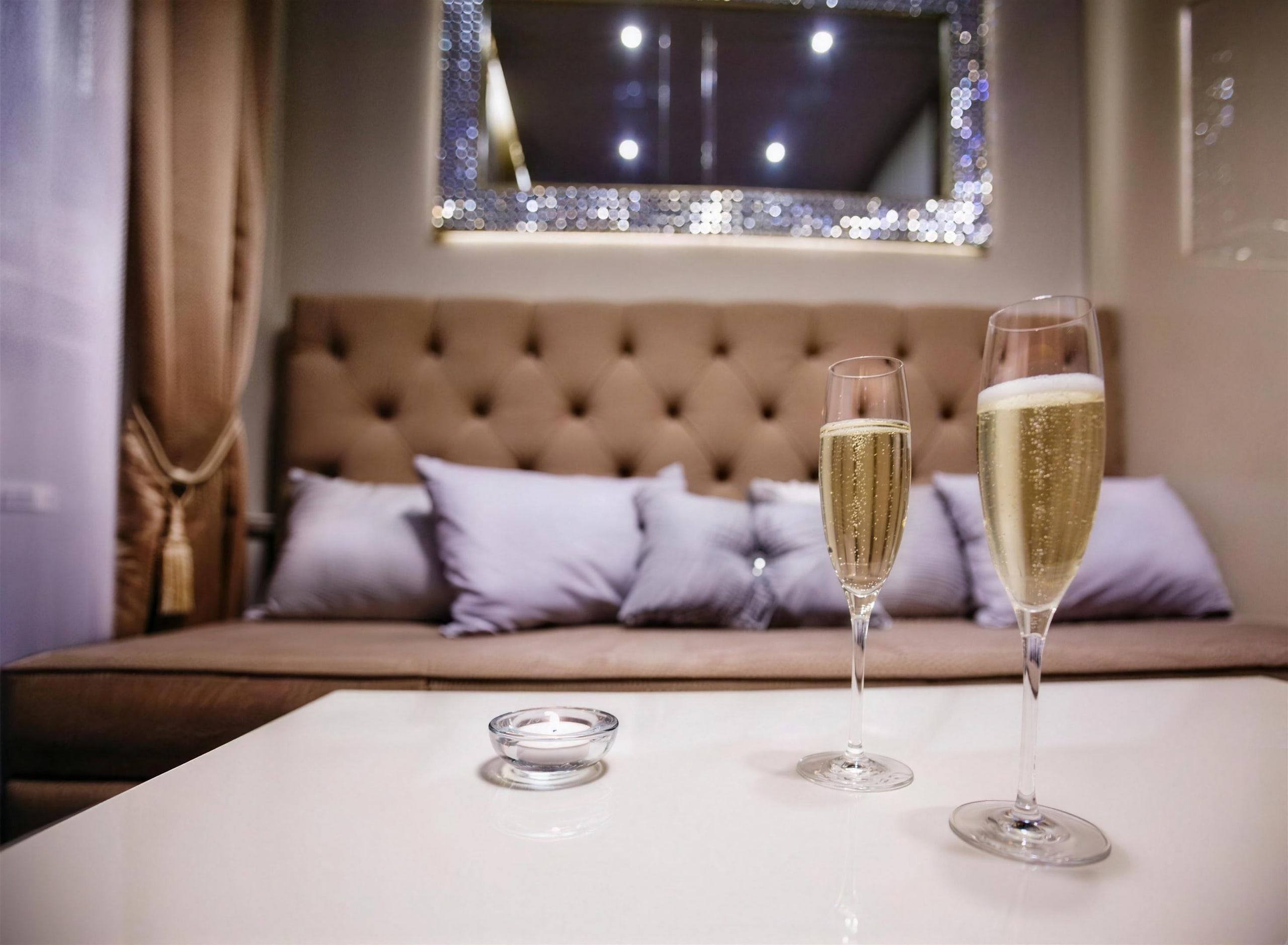 Two glasses of champagne on a table in front of the tufted sofa in the Diamant room