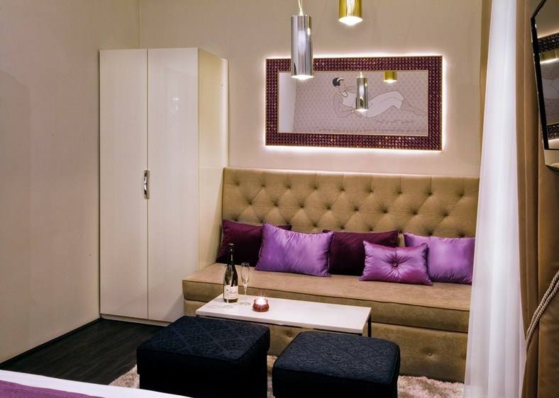 Sitting area in the Amethyst room with purple satin cushions, champagne and a candle