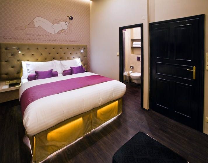 Amethyst room with double bed, purple cushions and a door to the bathroom